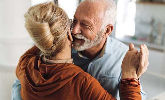 an older couple embraces and smiles together while looking at each other