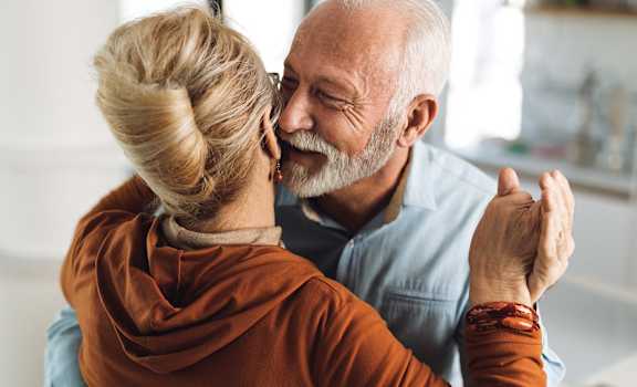 an older couple embraces and smiles together while looking at each other
