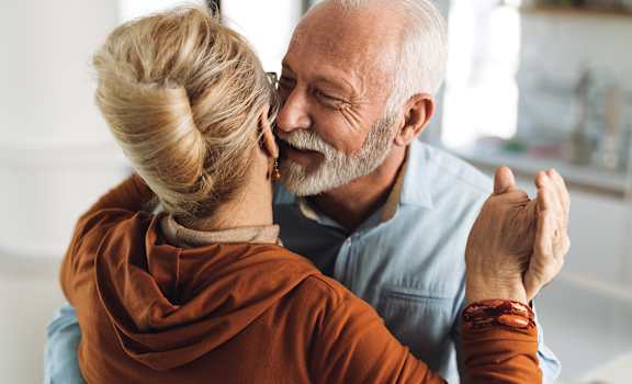 An older couple dancing together in a kitchen.