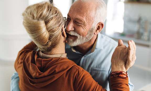 an older couple embraces and smiles together while looking at each other at Stetson Meadows Apartments, Colorado Springs, CO, 80922