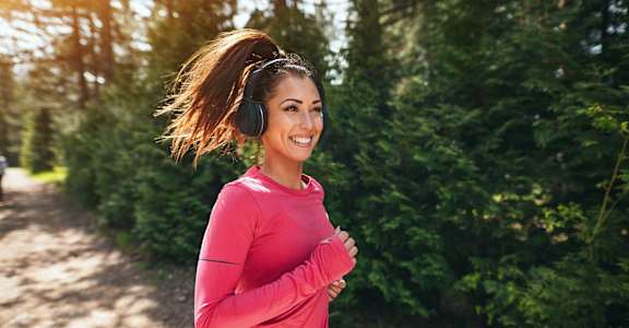 a woman running while wearing headphones and smiling