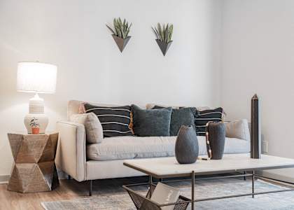 A living room with a grey couch, a white table, and a grey rug.