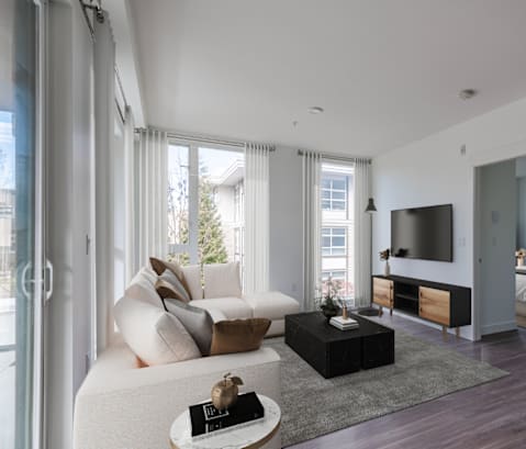 A modern living room with a white sofa, a black coffee table, and a TV.
