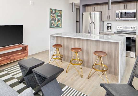 a kitchen and living room with a bar and stools