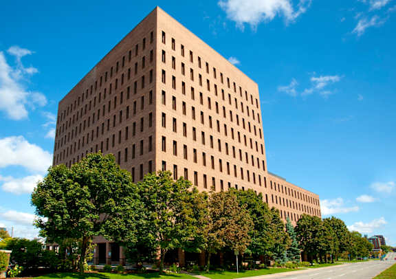 A large tan building with a lot of windows and trees in front of it.
