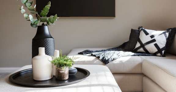 a living room with a couch and a table with vases and plants