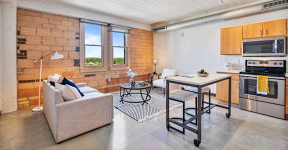 A living room with a couch, a table, and a brick wall.