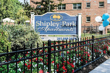 A sign for Shipley Park Apartments is displayed in front of a brick building.