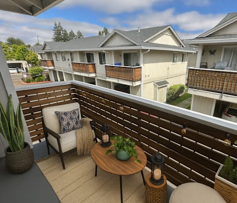 A balcony with a chair, table, and potted plants.