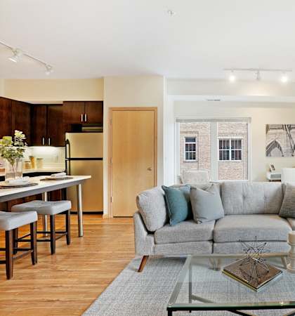 A modern living room with a grey couch and a glass coffee table.