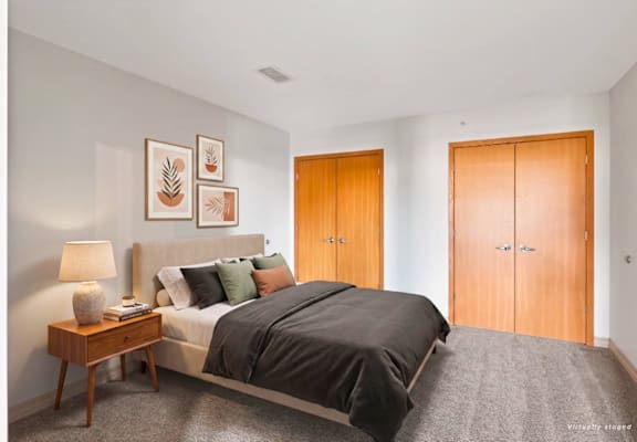 A bedroom with a bed, nightstand, and two doors.