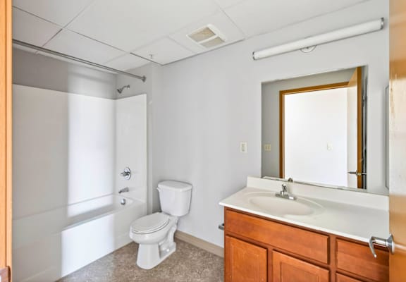 A white toilet sits in a bathroom next to a sink and a mirror.