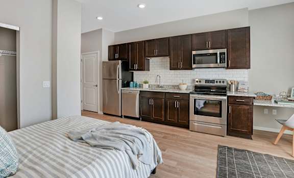 A modern kitchen with a bed in the foreground.