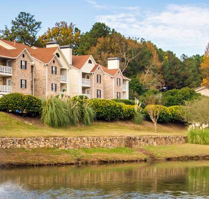 A large house with a stone wall and a pond in front.