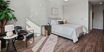 A bedroom with a bed, nightstand, and chair.