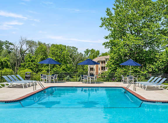 A swimming pool surrounded by lawn chairs and umbrellas.