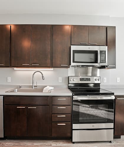 A modern kitchen with dark wood cabinets and stainless steel appliances.