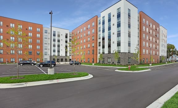 A street view of a residential area with apartment buildings and parked cars.