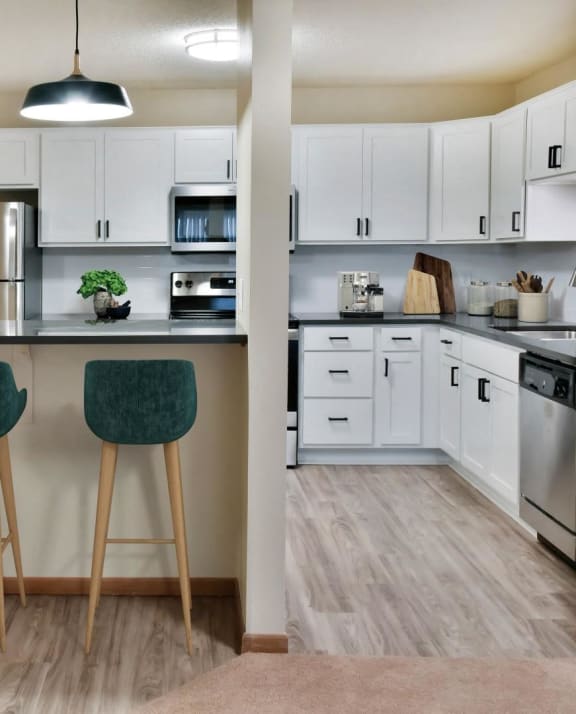 an open kitchen with white cabinets and a counter with three stools