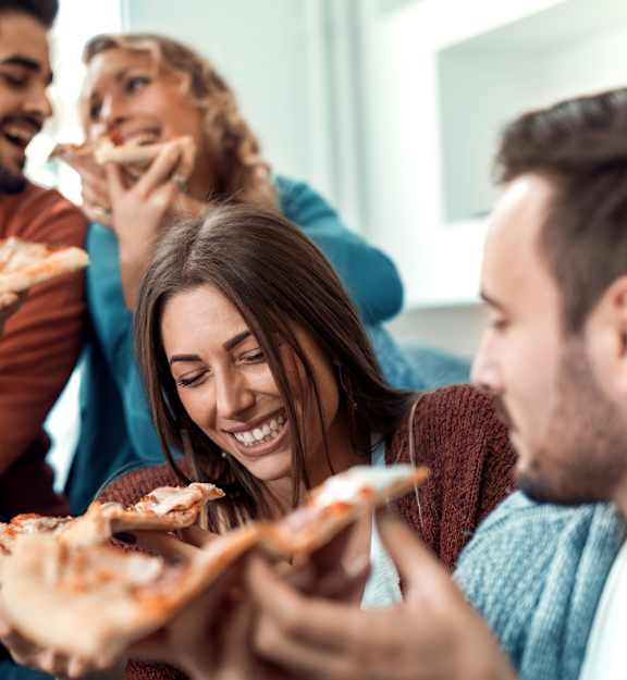 Four people enjoying pizza together in a casual setting.
