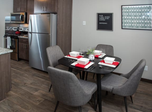 a dining area with a table and chairs and a kitchen in the background