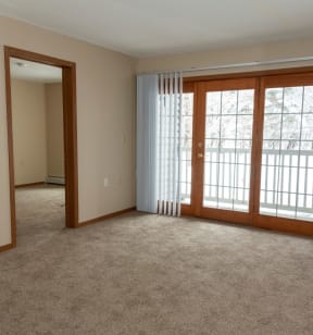 an empty living room with sliding glass doors and carpet