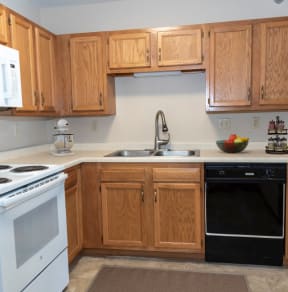 a kitchen with white appliances and wooden cabinets  at Briarcliff Apartments, a 55+ Community, Minnesota