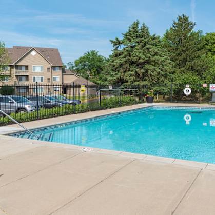a swimming pool with a fence and trees in the background