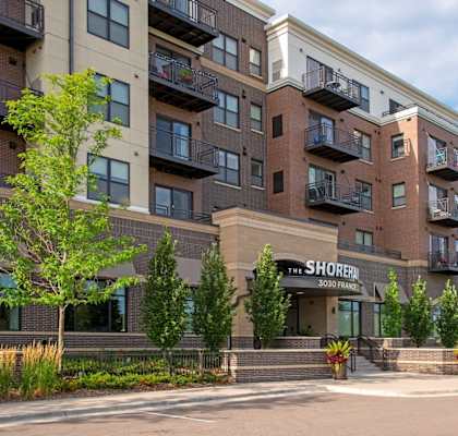 The Shorebird apartment complex is a multi-story building with balconies and a parking lot in front.