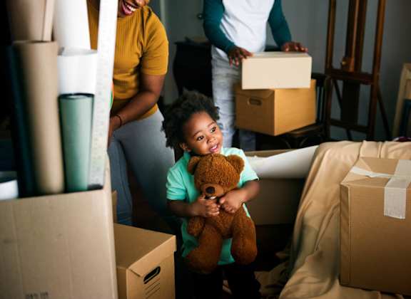 A woman and a child are surrounded by moving boxes.