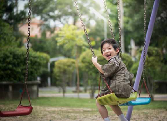 A young boy is swinging on a swing in a park.