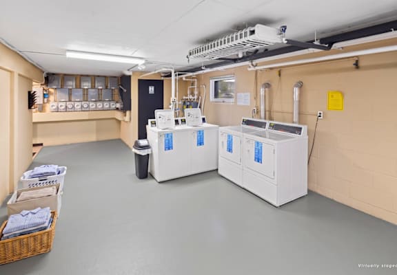 A room with two large white machines and a basket of towels on the left.