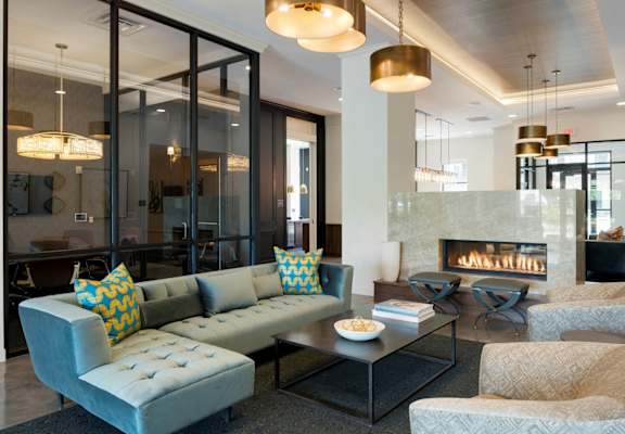 A modern living room with a grey couch and a fireplace.