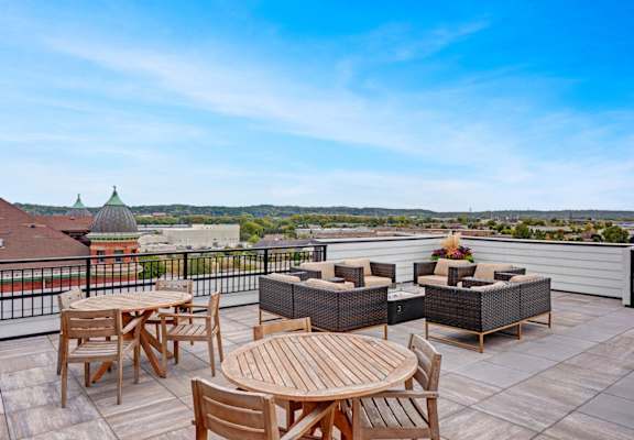 a rooftop patio with tables and chairs and a view of the city
