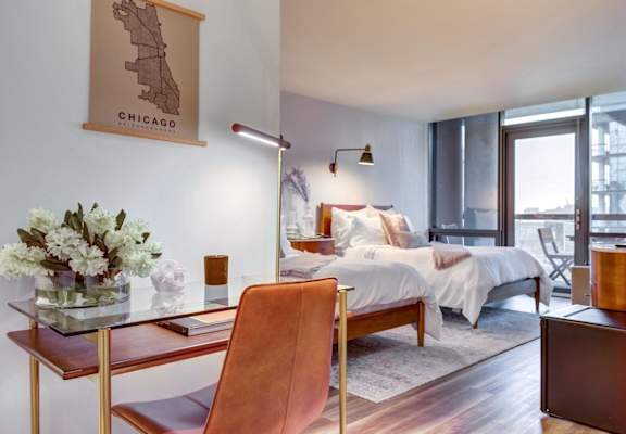 A bedroom with a bed, desk, and chair.