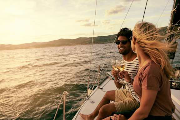 man and woman drinking wine on a sailboat