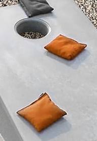 A grey cutting board with a knife and two square brown objects on it.