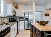Thumbnail 16 of 35 - a kitchen with white cabinets and black countertops at East 51 At Rocketts Landing, Richmond, 23231