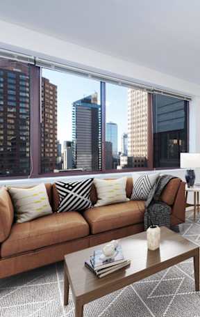 A modern living room with a brown sofa and a wooden coffee table at The Ellington Apartments, New York, NY, 10019