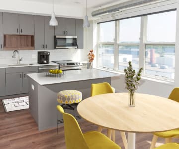 a kitchen with gray cabinets and a wooden table with yellow chairs