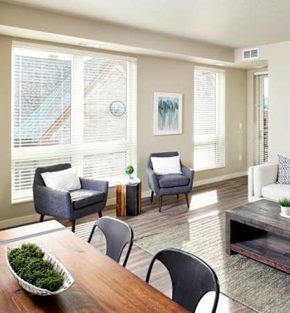 A living room with a white couch, grey armchairs, a wooden coffee table, and a painting on the wall. at The M on Hennepin, Minnesota, 55414