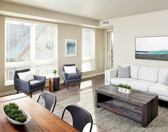 A living room with a white couch, grey armchairs, a wooden coffee table, and a painting on the wall. at The M on Hennepin, Minnesota, 55414