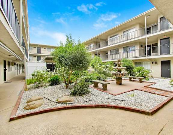 a courtyard with a fountain and benches in front of an apartment building