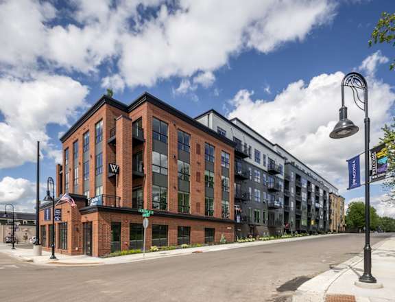 A street view of a building with a blue sky and clouds in the background.