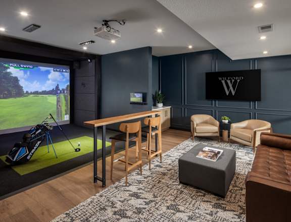 A modern living room with a golf simulator and a large TV.