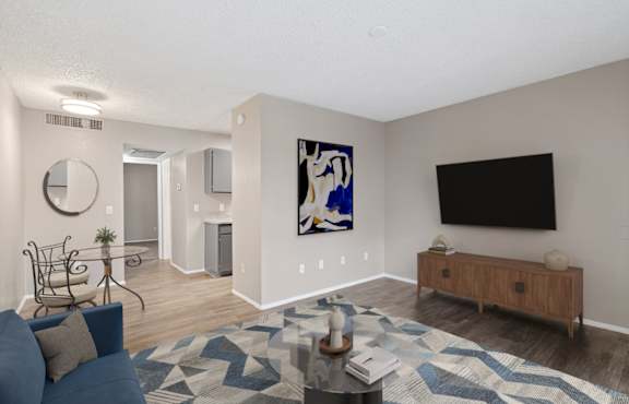 A living room with a blue couch and a painting on the wall.