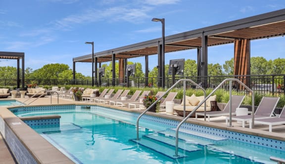 a resort style pool with lounge chairs and a pergola