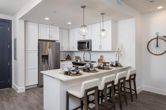 A modern kitchen with a white island and dark wood floors at 2020 Providence in Huntsville, AL