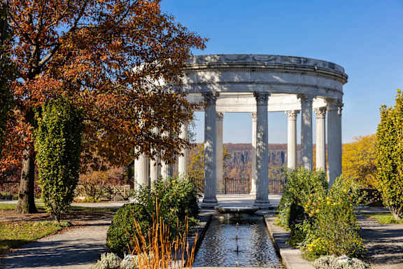 a park with a fountain and a building with columns
