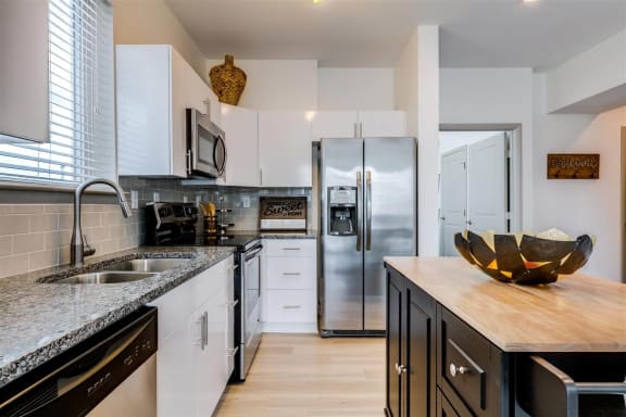 a kitchen with white cabinets and black countertops at East 51 At Rocketts Landing, Richmond, 23231